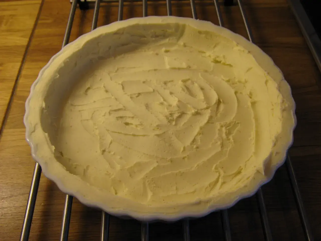 En ljusgul, krämig glutenfri pajdeg i en vit pajform, redo att fyllas.