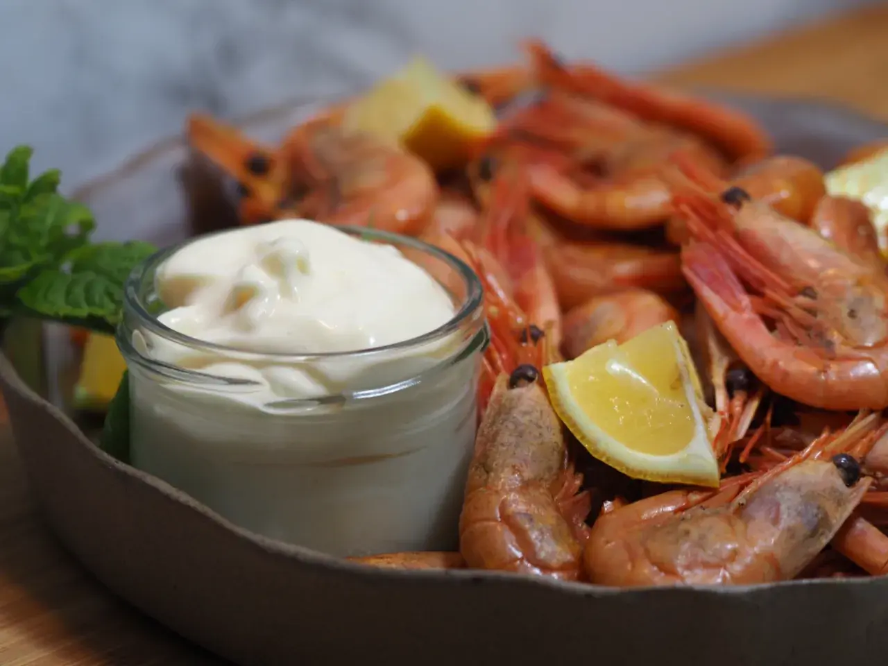 En skål med räkor och citronklyftor, med en liten burk krämig aioli. Perfekt för ett enkelt aioli recept.