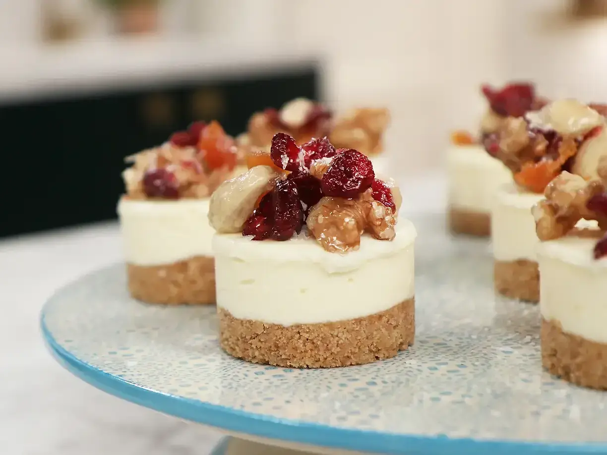 Små mini cheesecakes med nötter och torkad frukt på en blåmönstrad tårtfat.