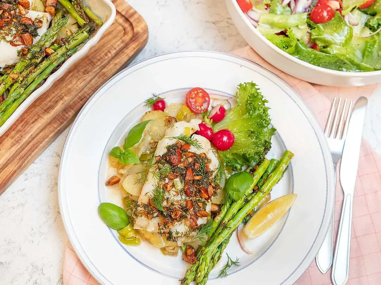 En portion torsk med citronsås, serverad med sparris, potatis och en fräsch sallad.