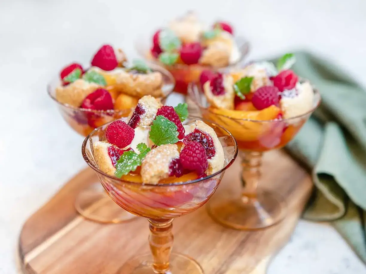 Tre eleganta glas med persika, hallon och smuldeg. En klassisk peach melba som ser ljuvlig ut.