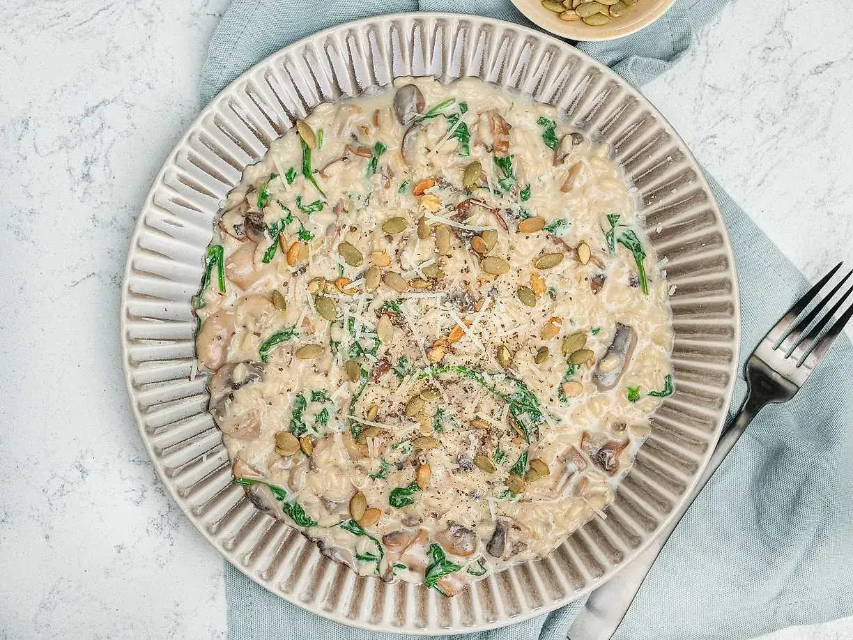 Krämig risotto svamp med spenat och pumpafrön, toppad med parmesan och svartpeppar. En härlig rätt som värmer själen.