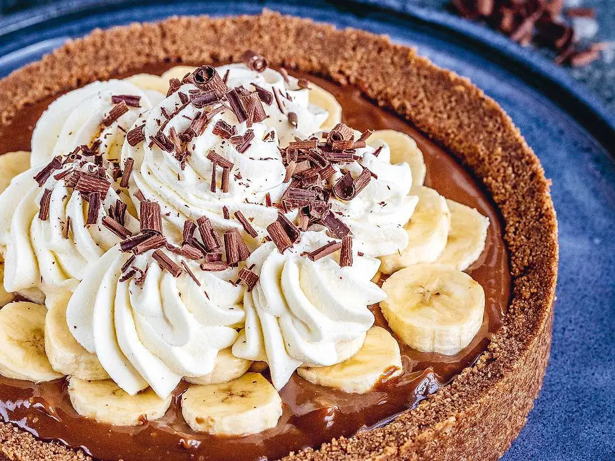 En krämig banoffee paj med vispgrädde, bananskivor och chokladströssel. En dröm för alla sötsugna!