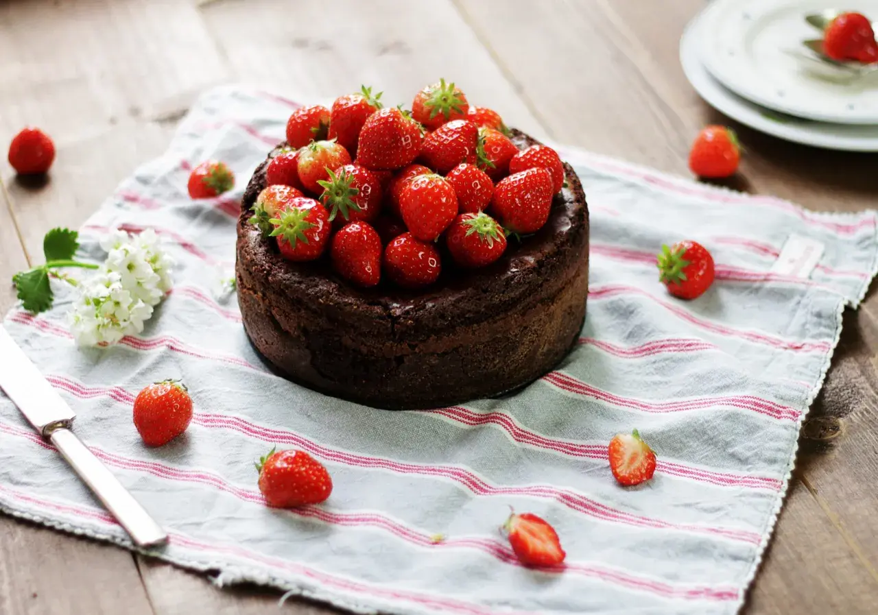 En kladdkaka med nutella, toppad med färska jordgubbar, ligger på en randig duk.