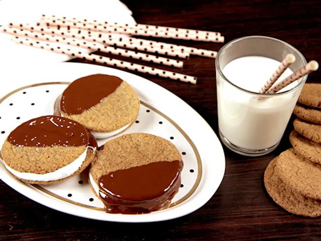 S'mores i ugn: tre chokladöverdragna kex med marshmallowfyllning på en prickig tallrik, bredvid ett glas mjölk och fler kex.