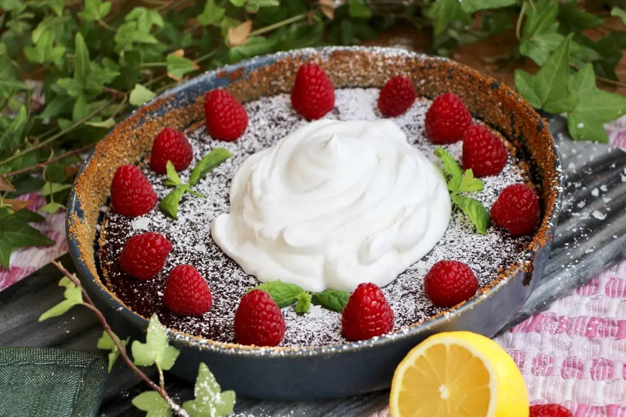 En härlig vegansk kladdkaka med fluffig grädde, färska hallon och myntablad. En perfekt dessert för alla tillfällen.