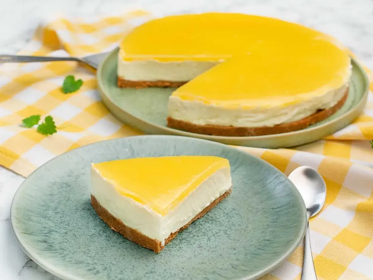 En krämig citron cheesecake med gul topping, en bit serverad på en tallrik.