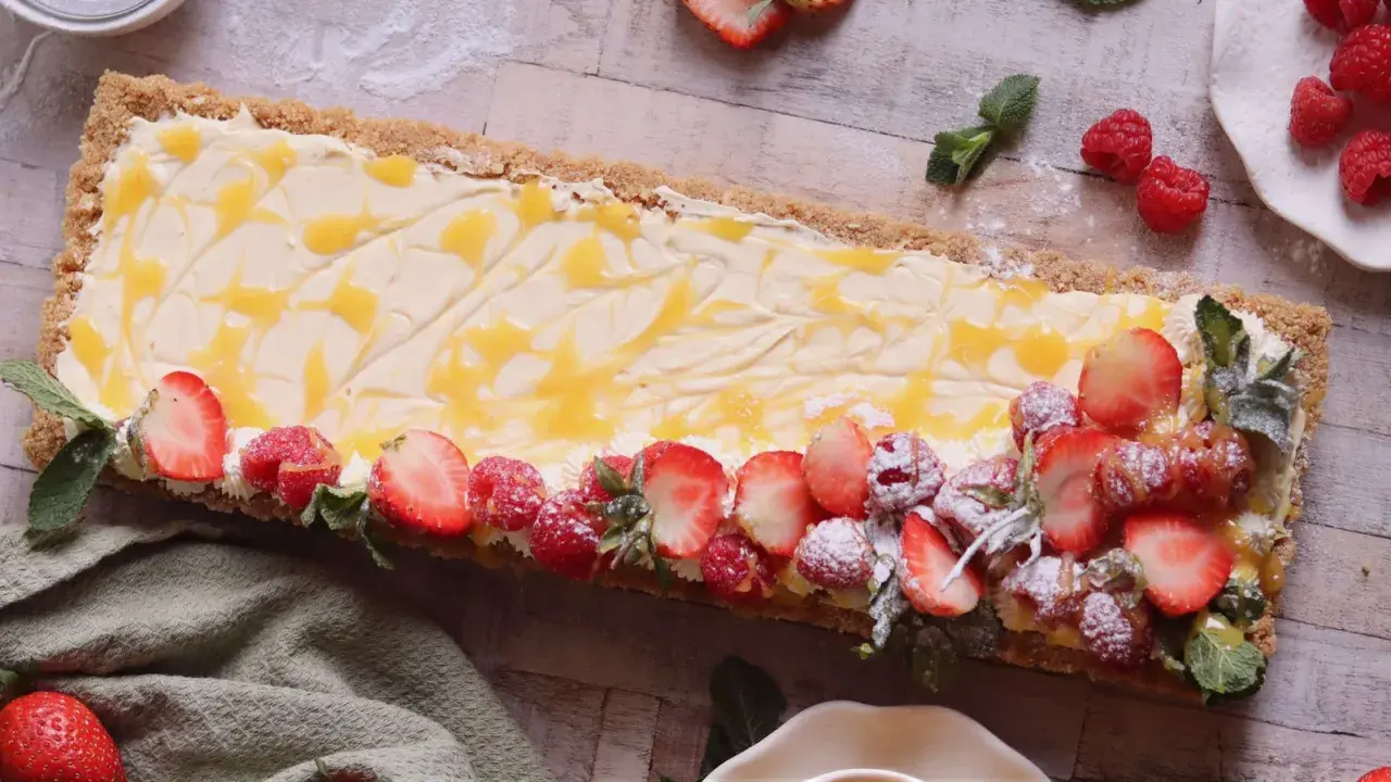 En avlång cheesecake med passionsfrukt, toppad med färska jordgubbar, hallon och mynta.