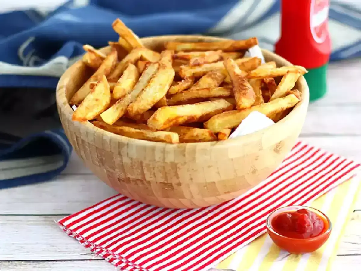 En skål med gyllene, krispiga egna pommes frites, redo att doppas i ketchup.