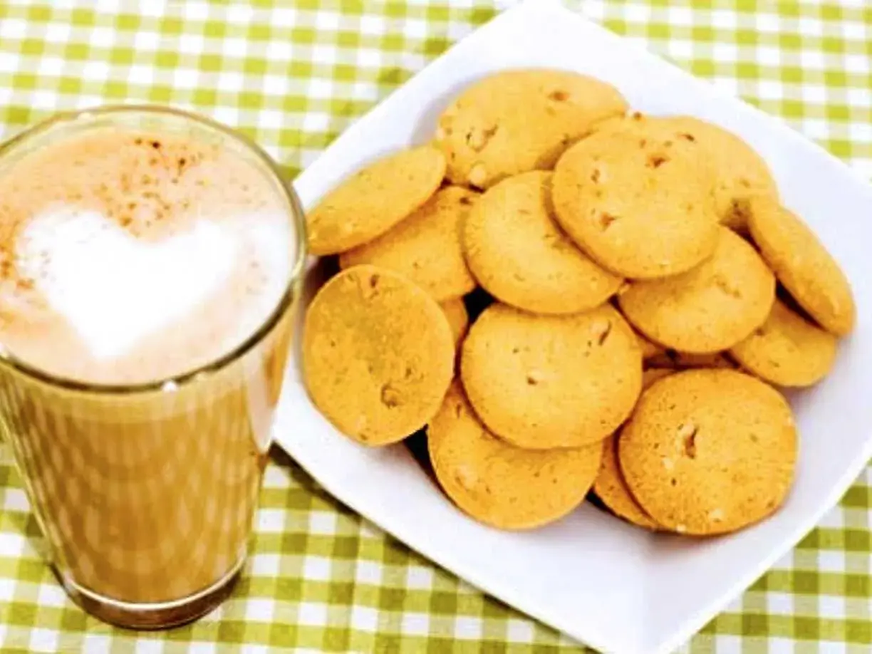 En kopp kaffe med hjärtformad lattekonst bredvid en hög med gyllene bondkakor. Perfekt för ett mysigt fika med detta bondkakor recept.