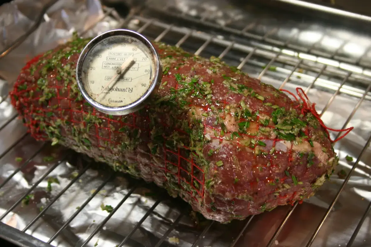 En fransyska i ugn, förberedd för låg temperaturstekning med örtkryddor och en köttermometer.