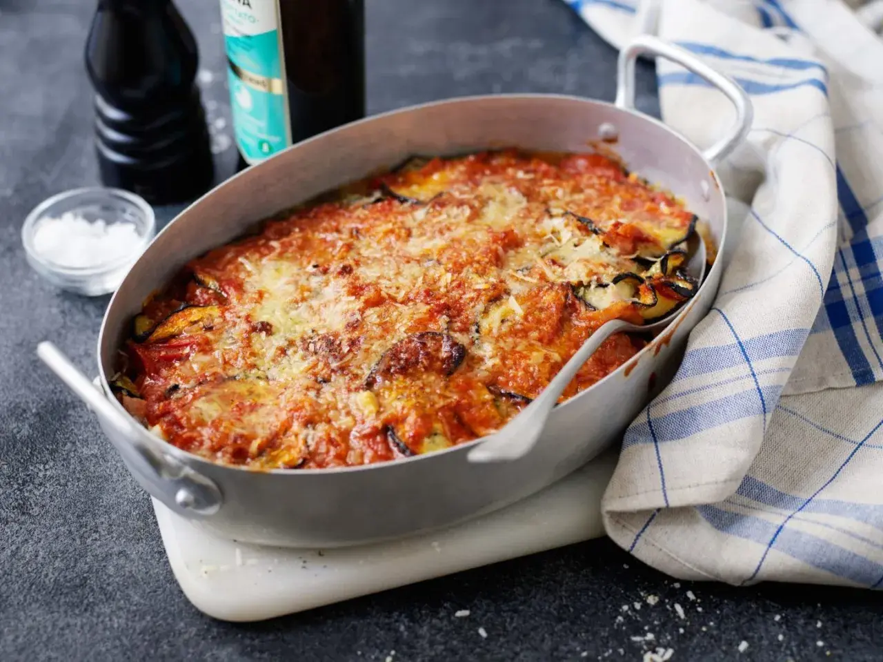 En ugnsform med en gyllene, bubblande melanzane alla parmigiana, toppad med riven ost och tomatsås. En klassisk italiensk rätt som doftar ljuvligt.
