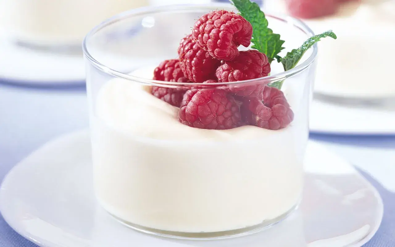 En len vit chokladmousse i glas, toppad med färska hallon och en myntakvist. En perfekt dessert för alla tillfällen.