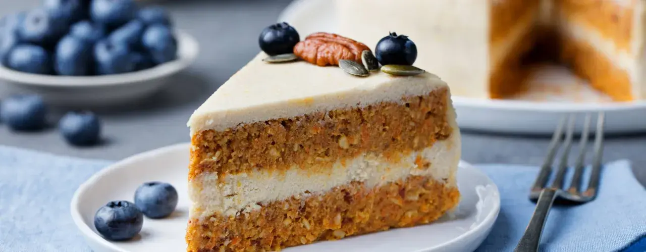 En saftig bit vegansk morotskaka med krämig frosting, toppad med blåbär och pekannöt. En härlig fika!