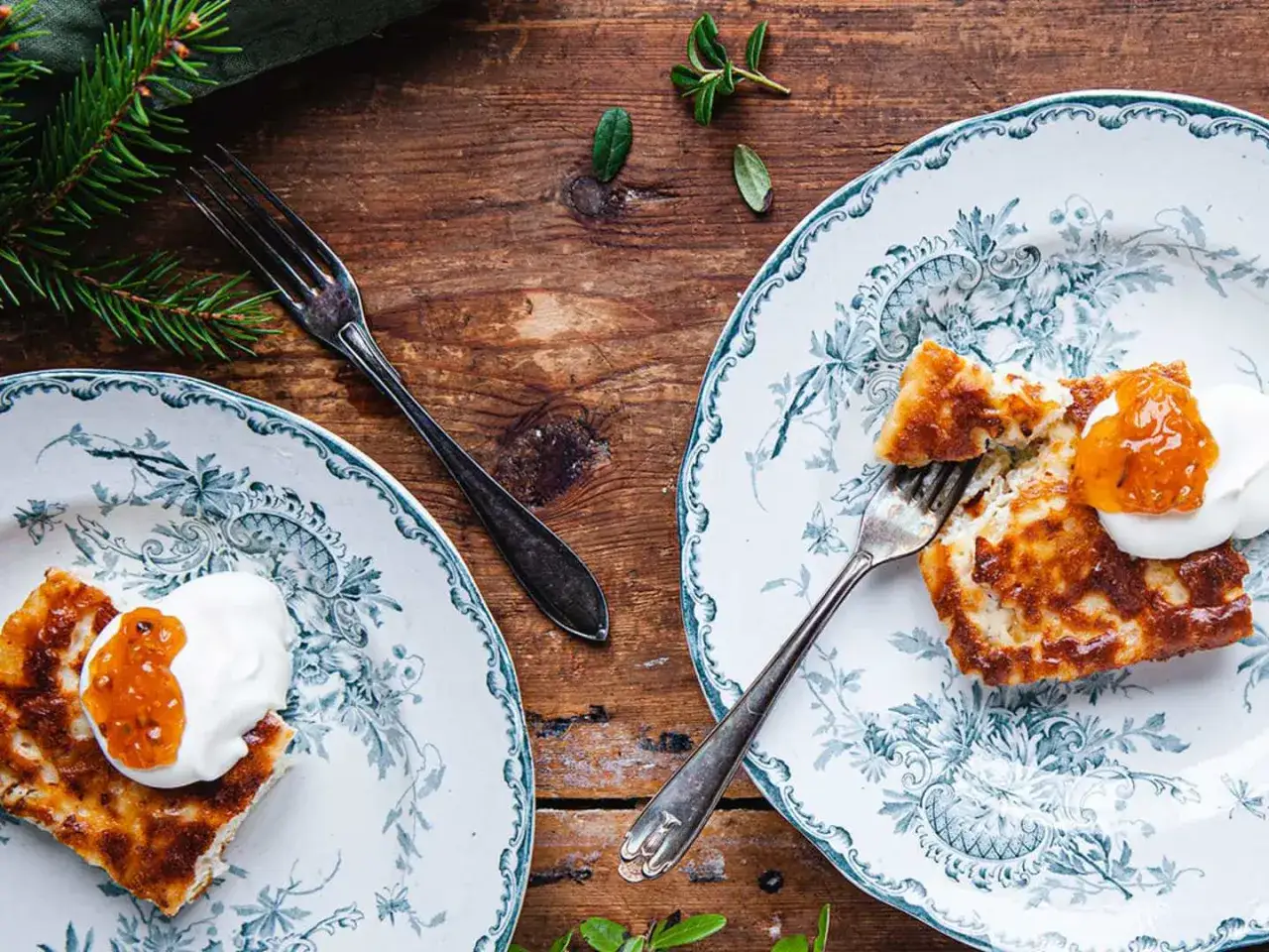 Två tallrikar med gyllene ostkaka, toppad med grädde och aprikosmarmelad. En härlig ostkaka keso-inspirerad dessert.
