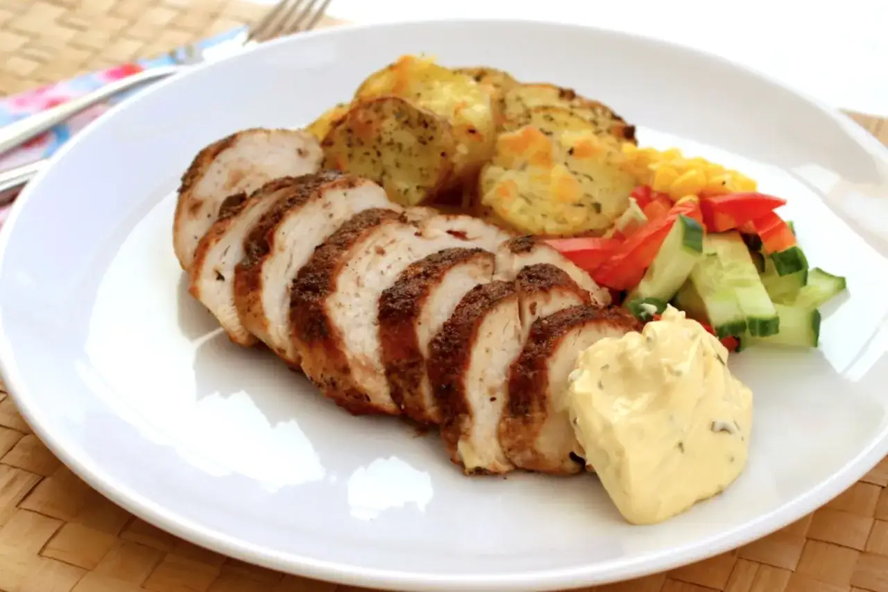 Skivad, grillad kycklinglårfilé med rostade potatisskivor, majs, paprika, gurka och en klick aioli.