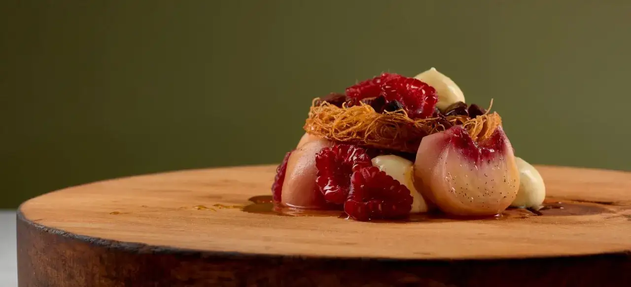 En konstnärlig dessert med persika, hallon och krämig vanilj, en modern tolkning av peach melba.