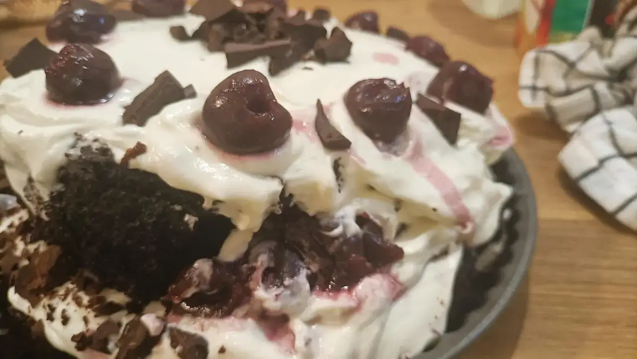 En bit av en Schwarzwaldtårta med vispgrädde, körsbär och chokladspån. Perfekt för ett Schwarzwaldtårta recept.