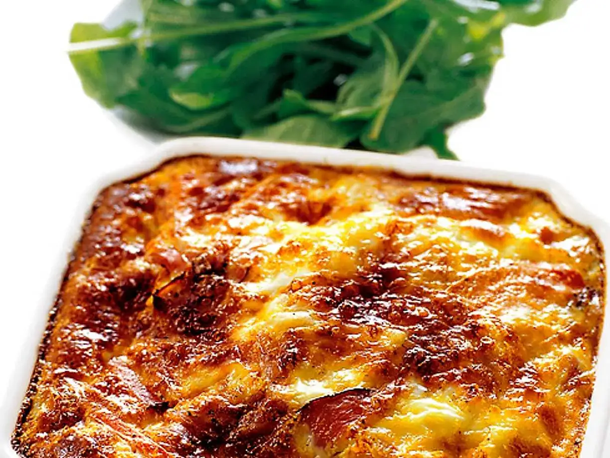 En gyllene makaronipudding i en vit form, med en sallad av ruccola i bakgrunden. Ett perfekt recept f&ouml;r en mysig middag.