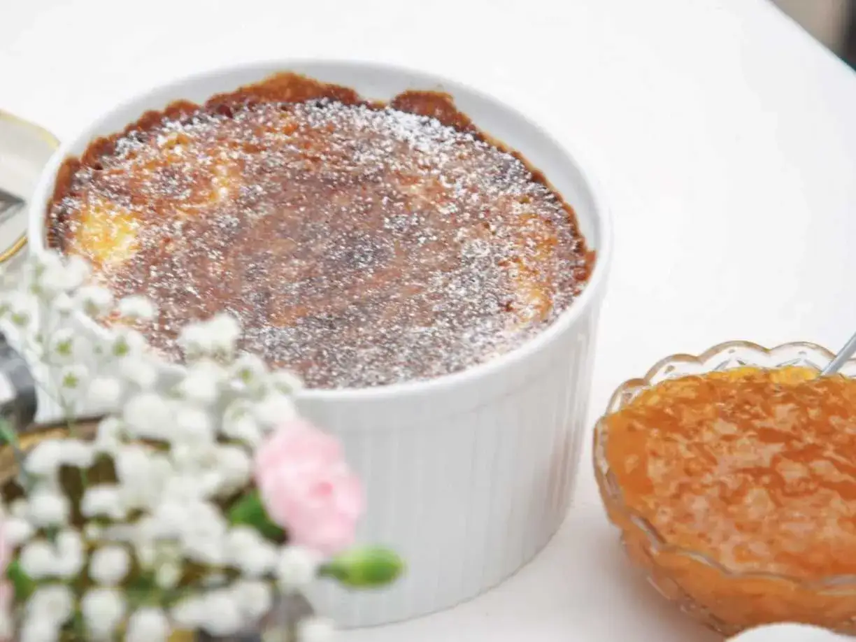 En gyllene ostkaka, perfekt för ett ostkaka recept, toppad med florsocker. Serveras med aprikosmarmelad.