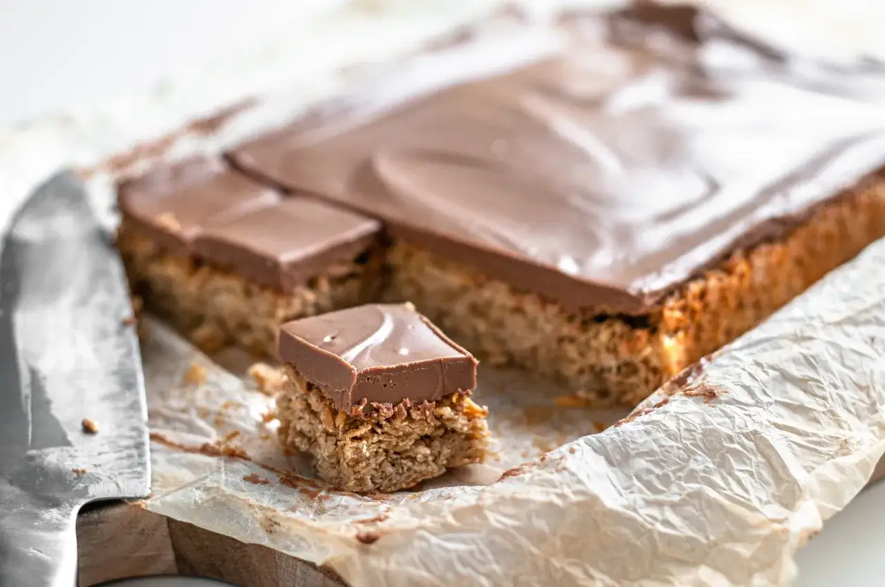 Nybakade nougatrutor i långpanna, redo att avnjutas. En bit är uppskuren och visar den krispiga botten och lena chokladtopping.