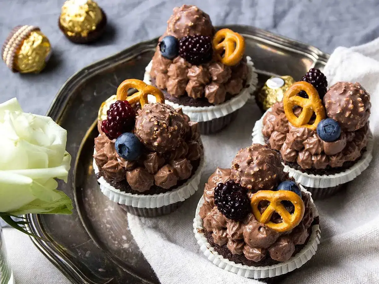 Lyxiga choklad cupcakes med chokladfrosting, bär, chokladbollar och små pretzels. En dröm för alla chokladälskare!