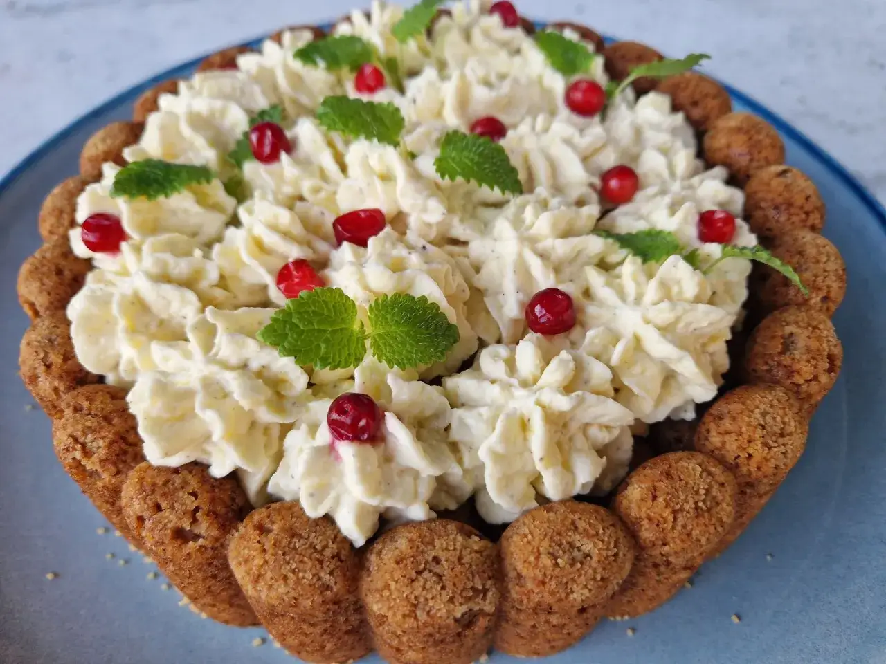 En mjuk pepparkaka med fluffig grädde, röda bär och gröna myntablad. En festlig dessert som doftar jul.