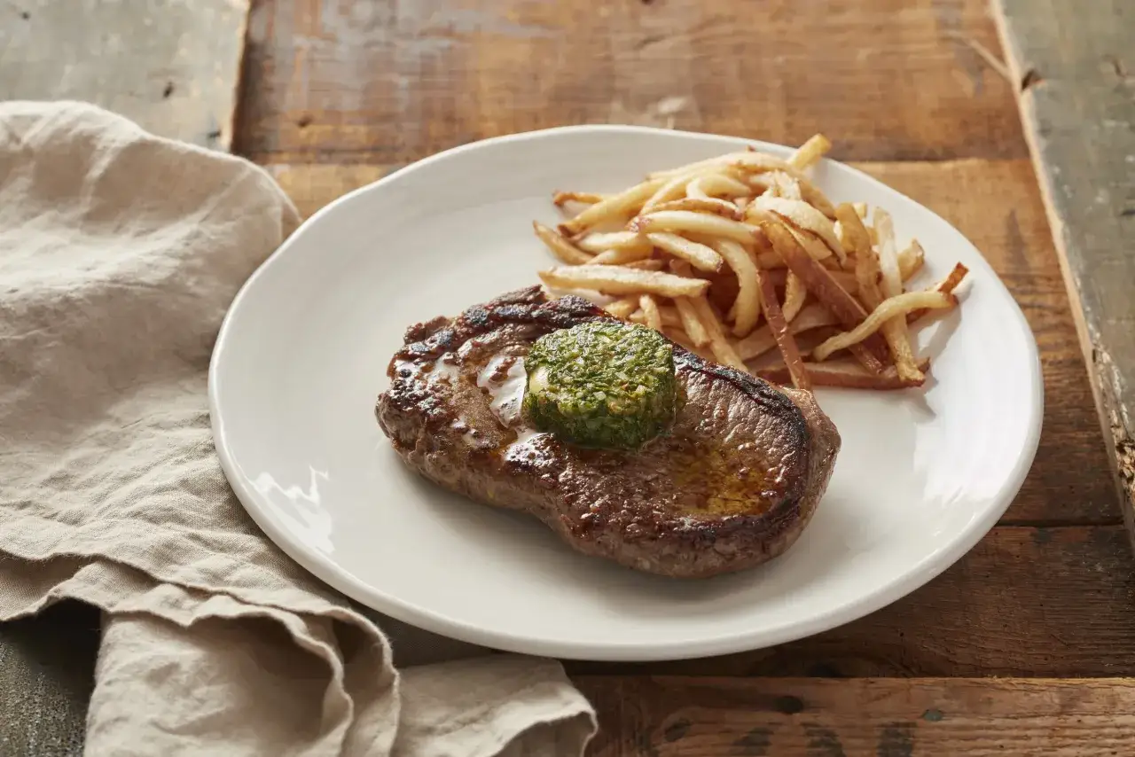 En saftig biff med pommes frites och en klick cafe de paris sås.