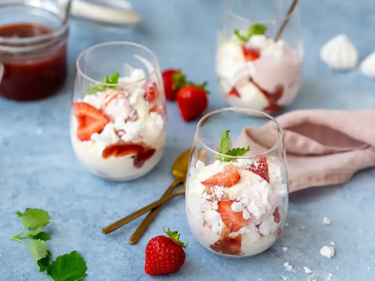 Tre glas med Eton Mess, en klassisk brittisk dessert med jordgubbar, maräng och grädde.