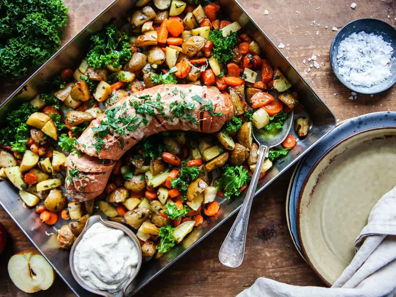 En saftig korv i ugn med rostade rotfrukter och gr&ouml;nk&aring;l. Serveras med en kr&auml;mig s&aring;s och en &auml;ppelklyfta.