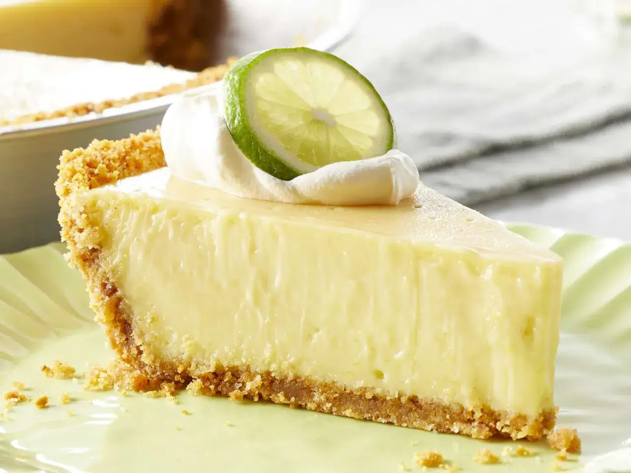 En krämig bit key lime pie med vispgrädde och en limeklyfta.