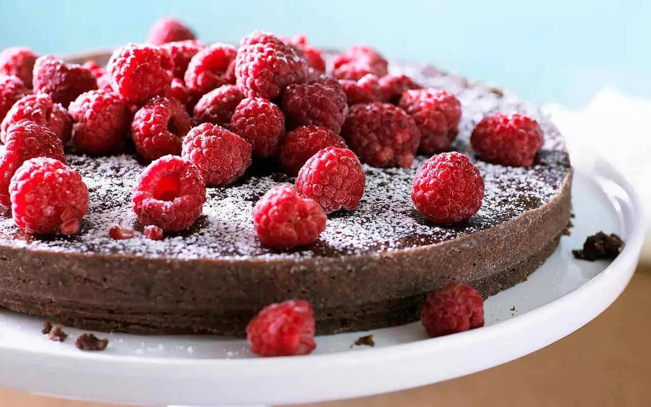 Kladdkaka med hallon, perfekt för kladdkakans dag och andra dagar. Pudrad med florsocker och toppad med färska hallon.