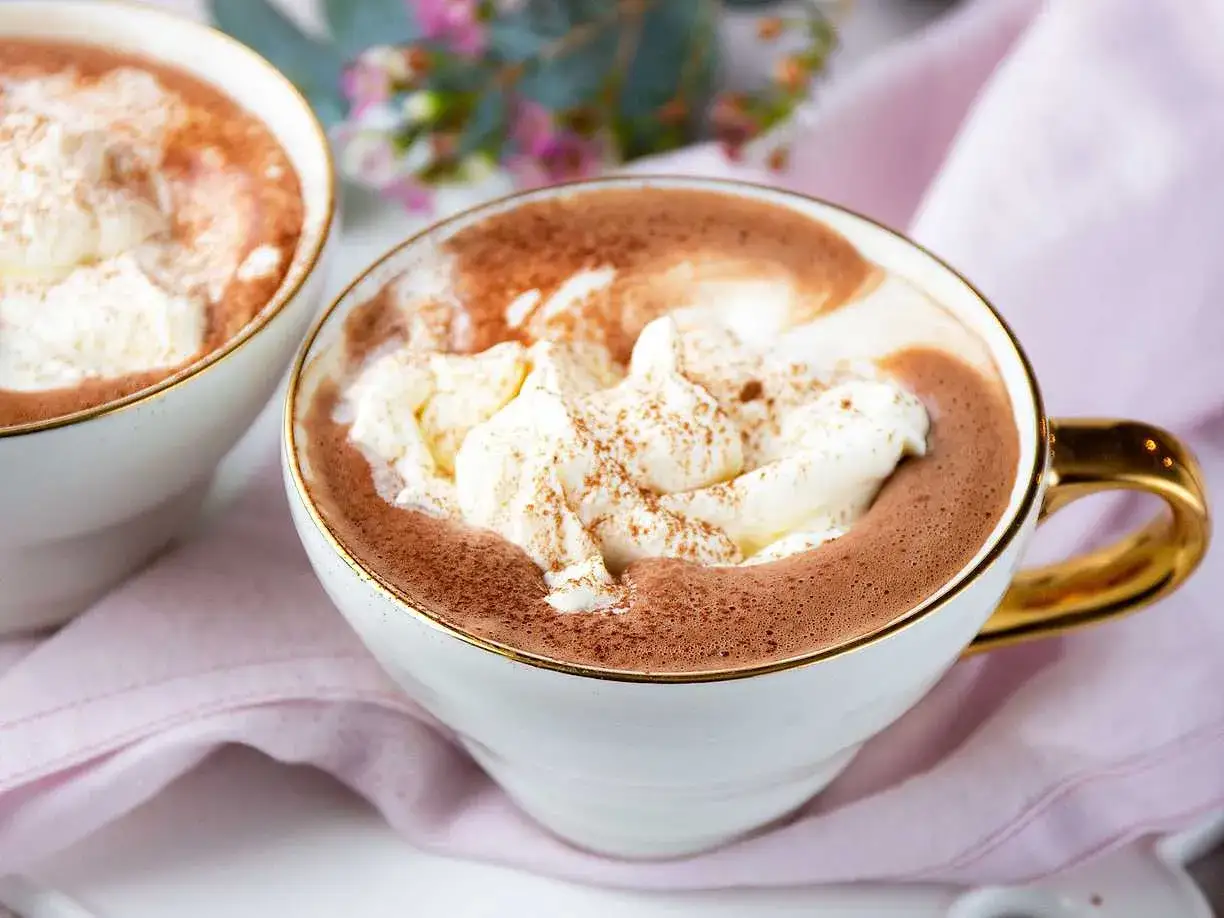Tv&aring; muggar med kr&auml;mig varm choklad, toppad med vispad gr&auml;dde och kanel. Perfekt f&ouml;r en mysig stund.