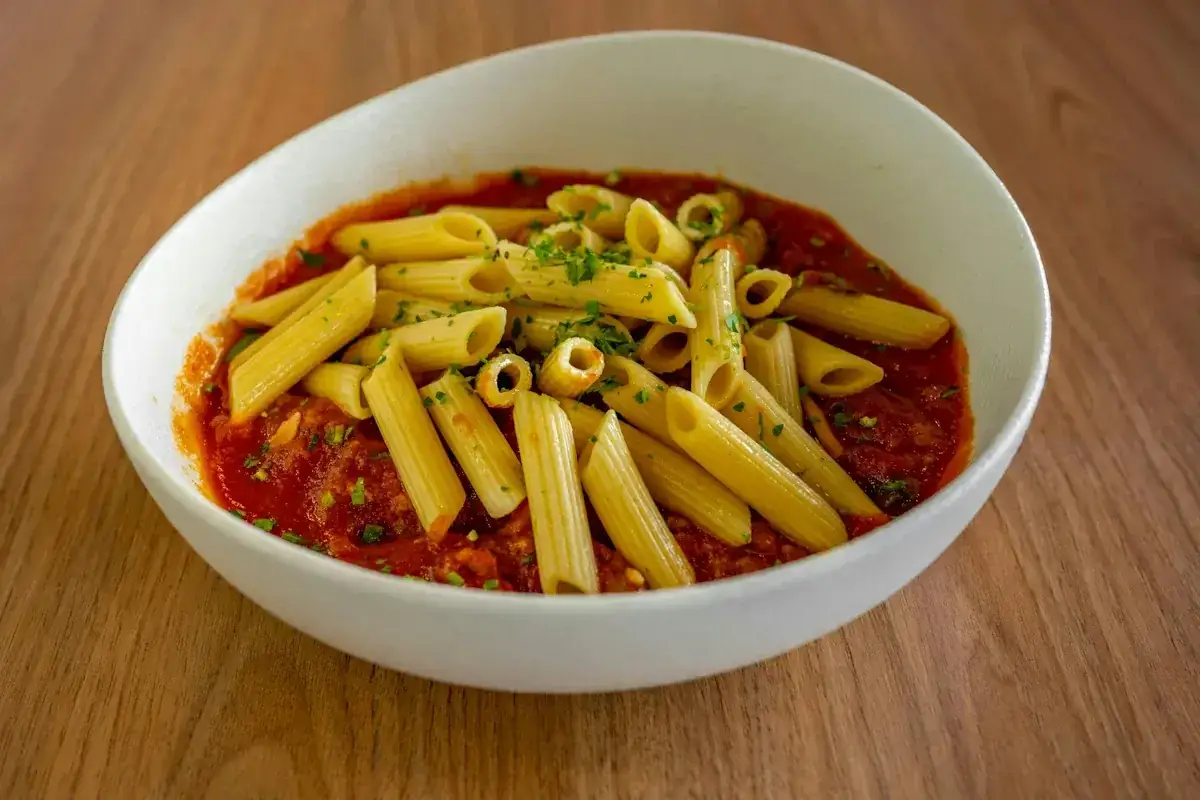 En skål med penne pasta i en mustig vegetarisk pastasås, toppad med färsk persilja. Enkel och god vardagsmat.