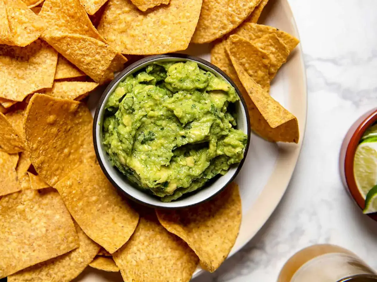 En sk&aring;l med kr&auml;mig guacamole omgiven av tortillachips. Perfekt f&ouml;r ett enkelt guacamole recept.