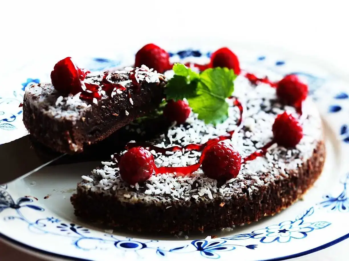 Kladdkaka med hallon och kokos, perfekt för ett enkelt kladdkaka recept. En bit lyfts fram.