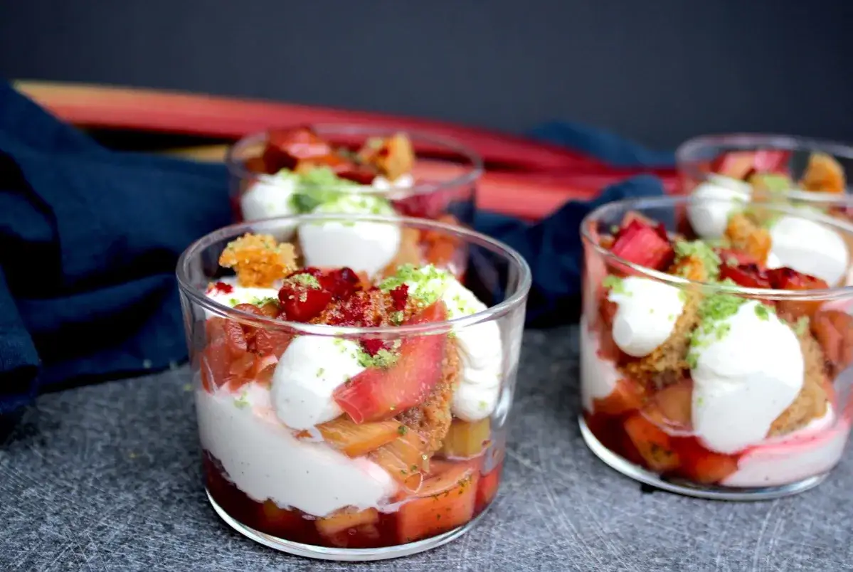 Flera glas med en läcker rabarberdessert, lager av krämig vanilj, söt rabarber och smulor.