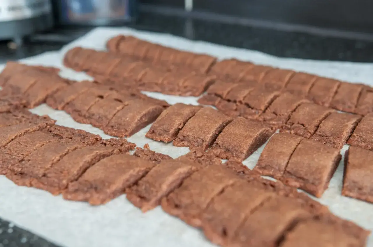 Rader av nybakade kolasnittar med choklad, redo att gräddas.