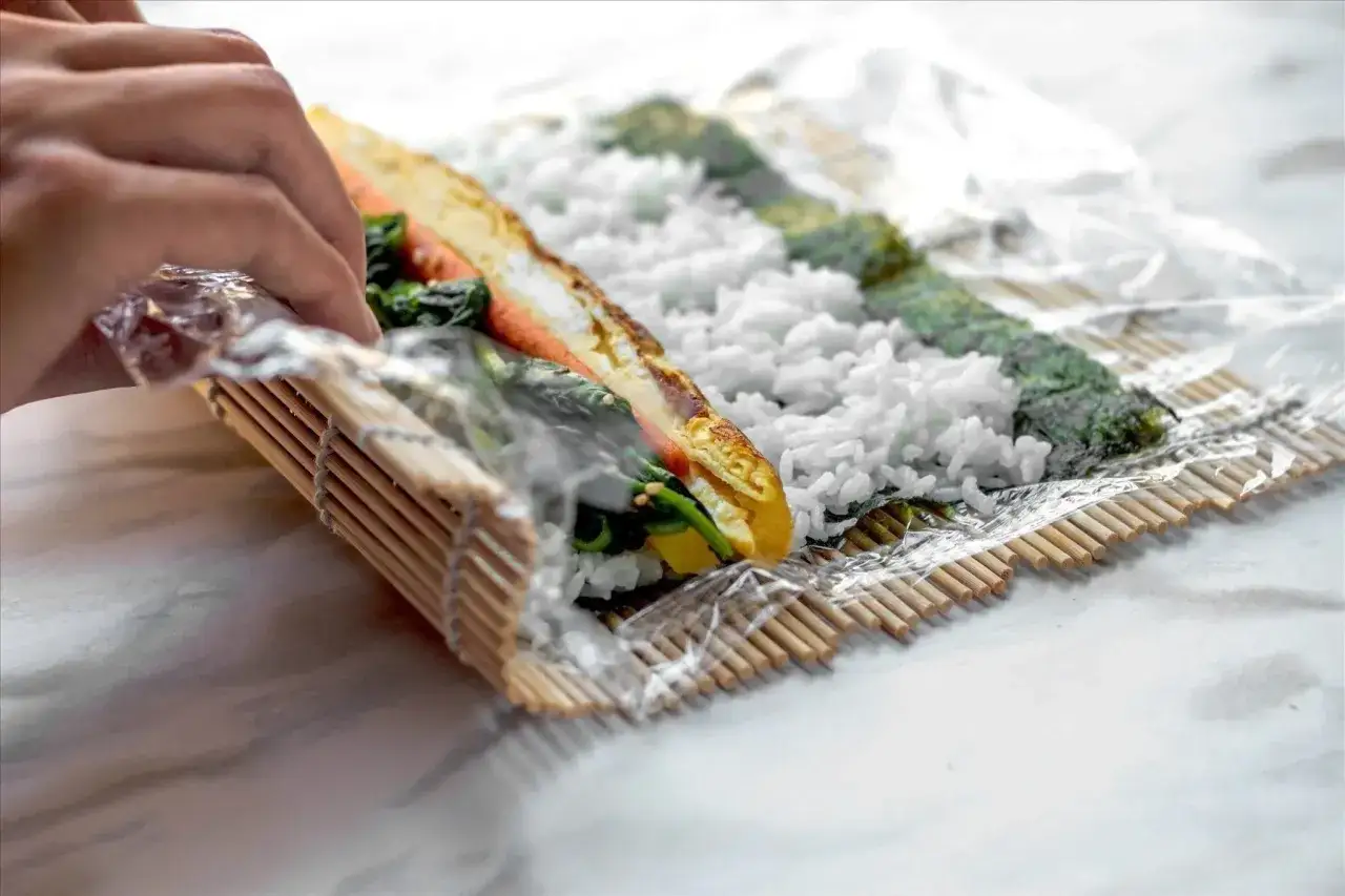 H&auml;nder rullar ihop en sushi med ris, nori, &auml;gg och gr&ouml;nsaker. Ett perfekt sushi recept att prova hemma.