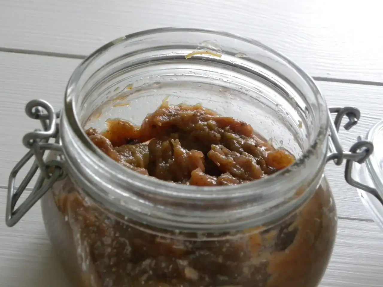 En burk med hemlagad rabarber chutney. Den &auml;r fylld med en mustig, brunaktig r&ouml;ra med bitar av rabarber.