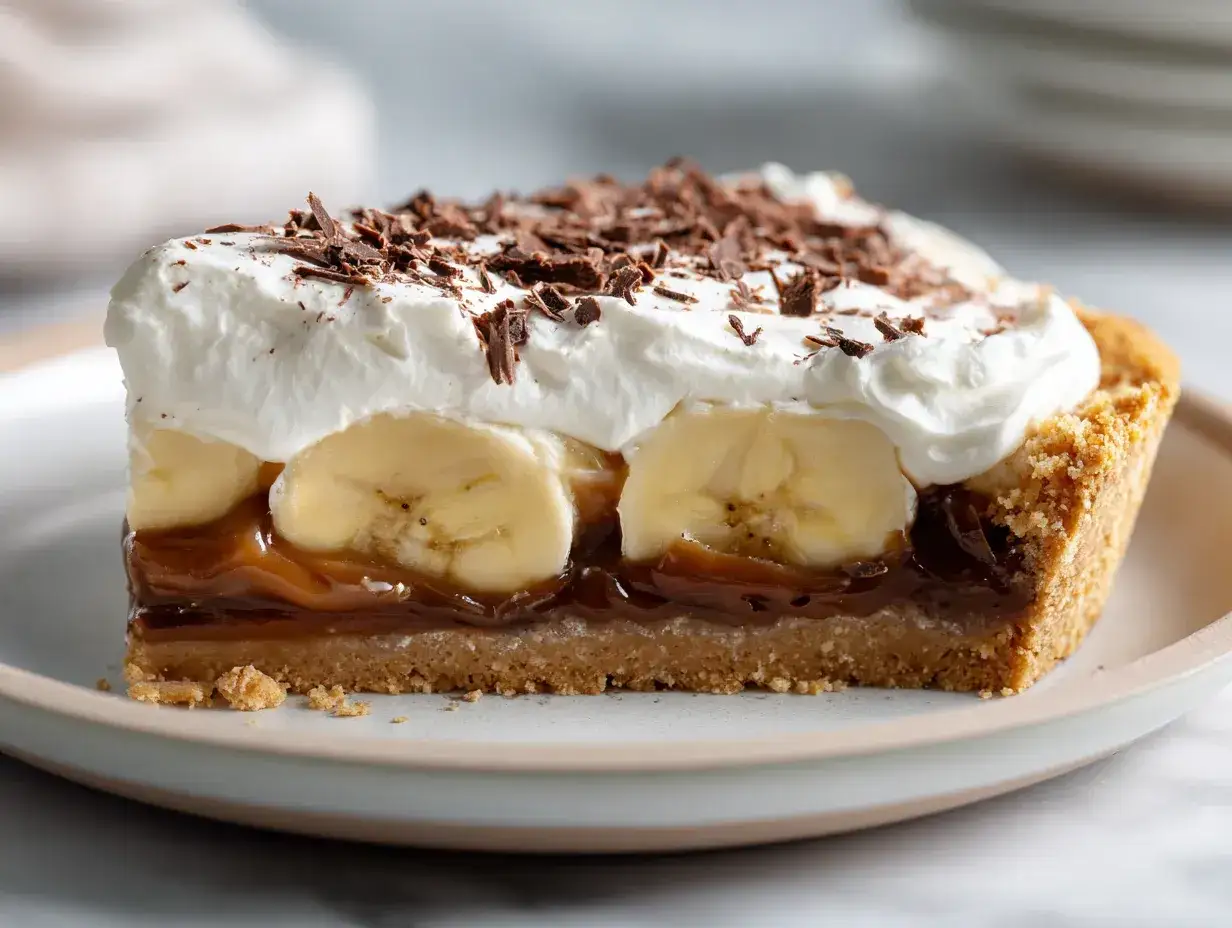 En bit krämig banoffee paj med banan, kolasås, vispgrädde och chokladströssel.