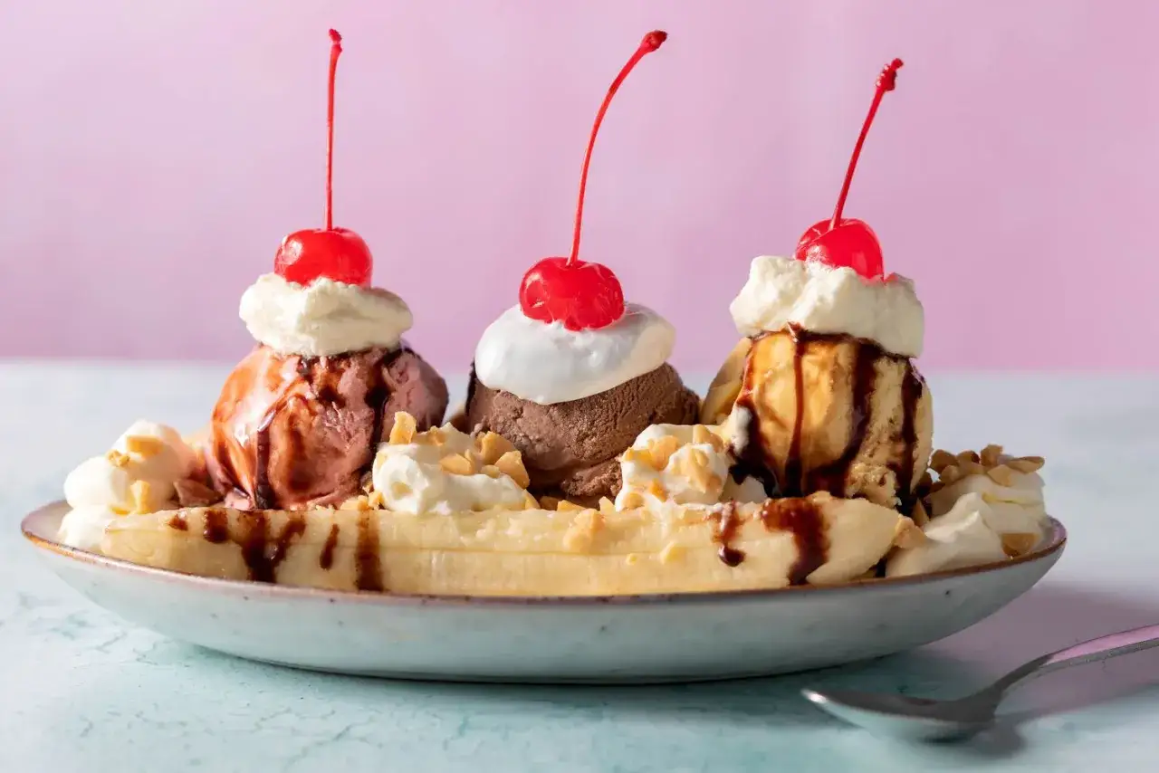 En klassisk banana split med tre kulor glass, banan, grädde, chokladsås och körsbär.