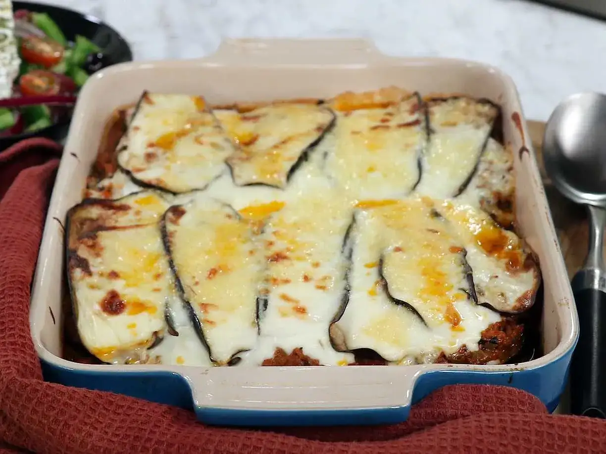 En ugnsform med en gyllene, bubblande moussaka, perfekt för ett mysigt middagsrecept.