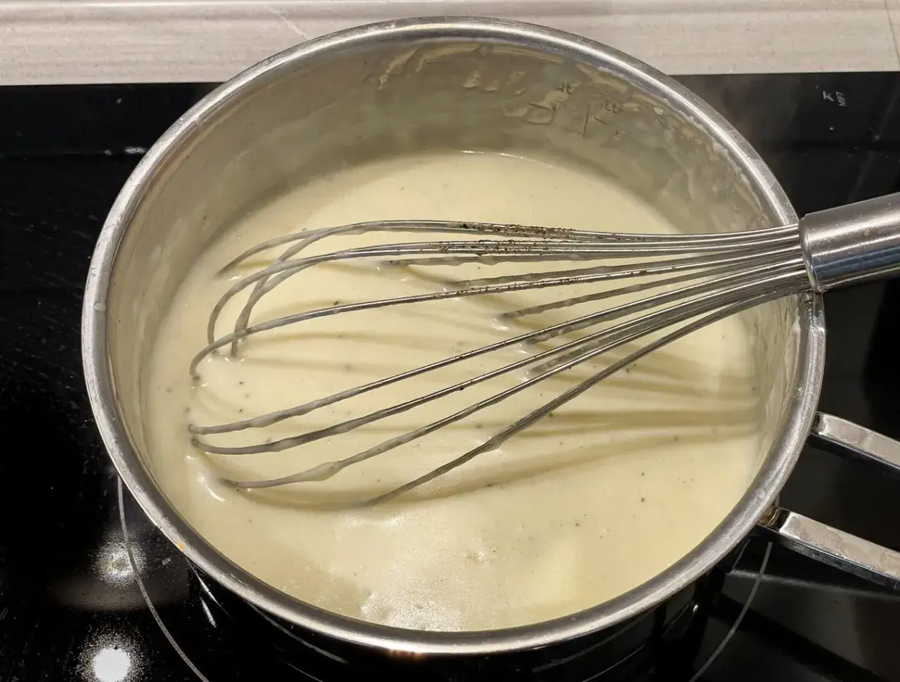 En krämig bechamelsås som vispas i en kastrull. Perfekt för ditt bechamelsås recept.