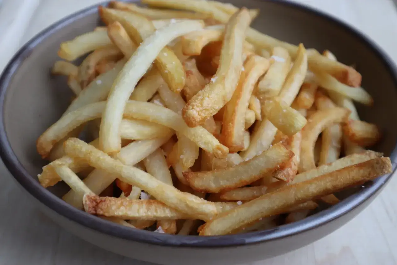 En skål med gyllene, salta egna pommes frites. Perfekt krispiga och redo att avnjutas.
