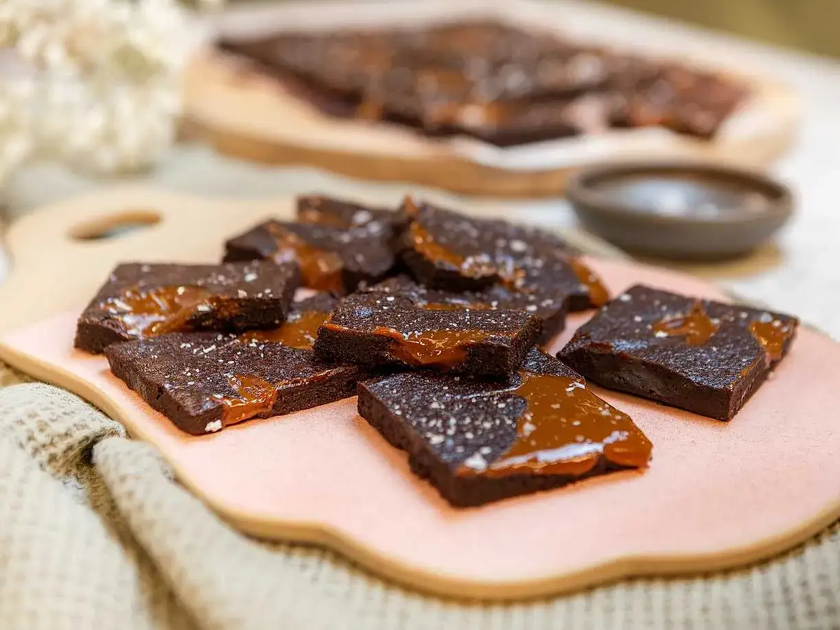 Mumsig kladdkaka i långpanna, skuren i bitar och toppad med salt karamellsås och flingsalt. Perfekt för fikat!