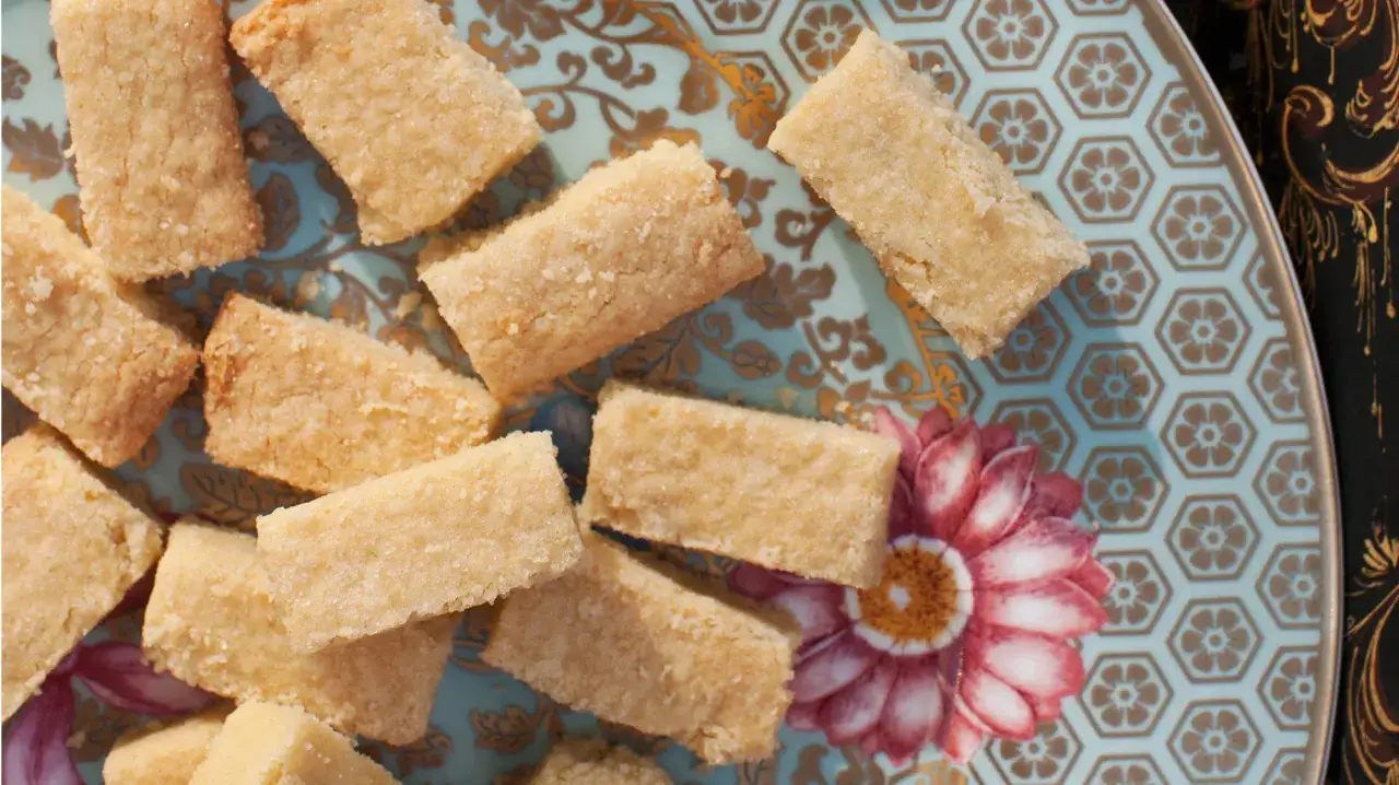 Små bitar av gyllene shortbread ligger utspridda på en vacker blå tallrik med blomstermönster. Perfekt för ett enkelt shortbread recept.