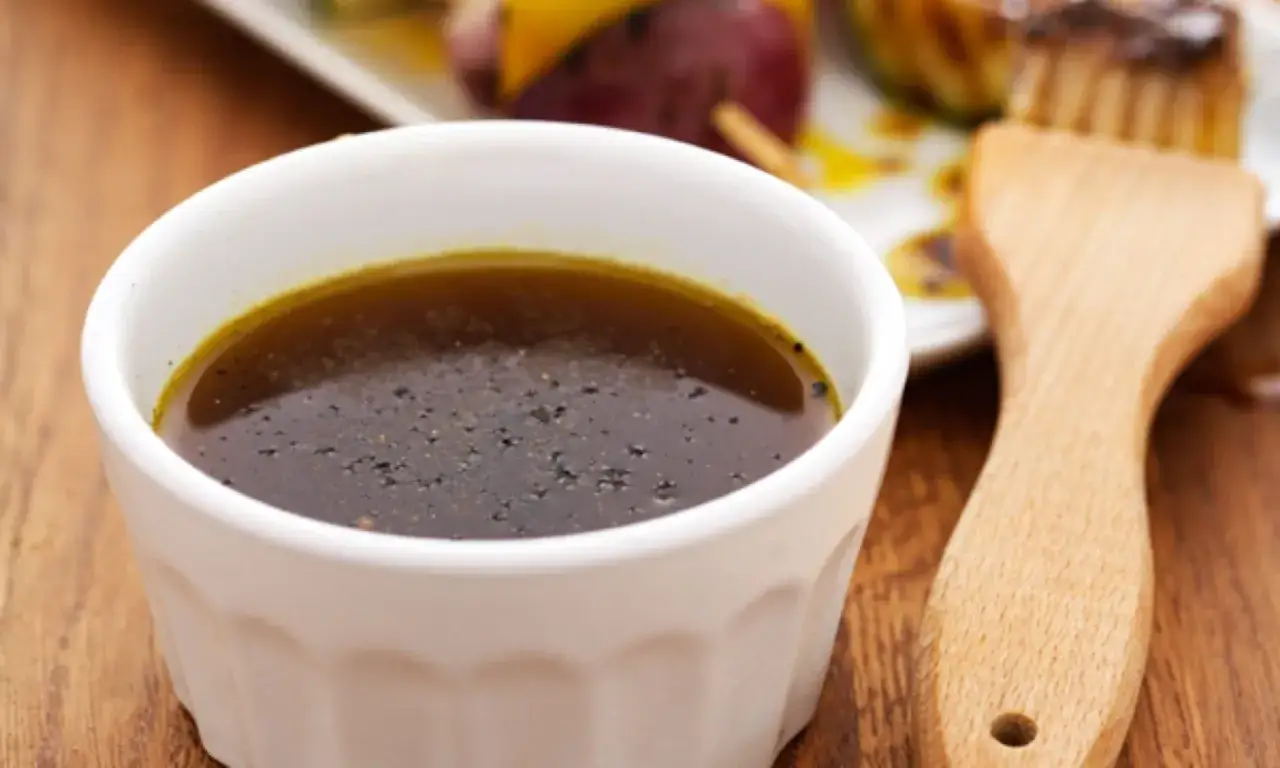 En sk&aring;l med m&ouml;rk marinad, perfekt f&ouml;r ditt n&auml;sta grillolja recept. En pensel ligger bredvid, redo att applicera smak.