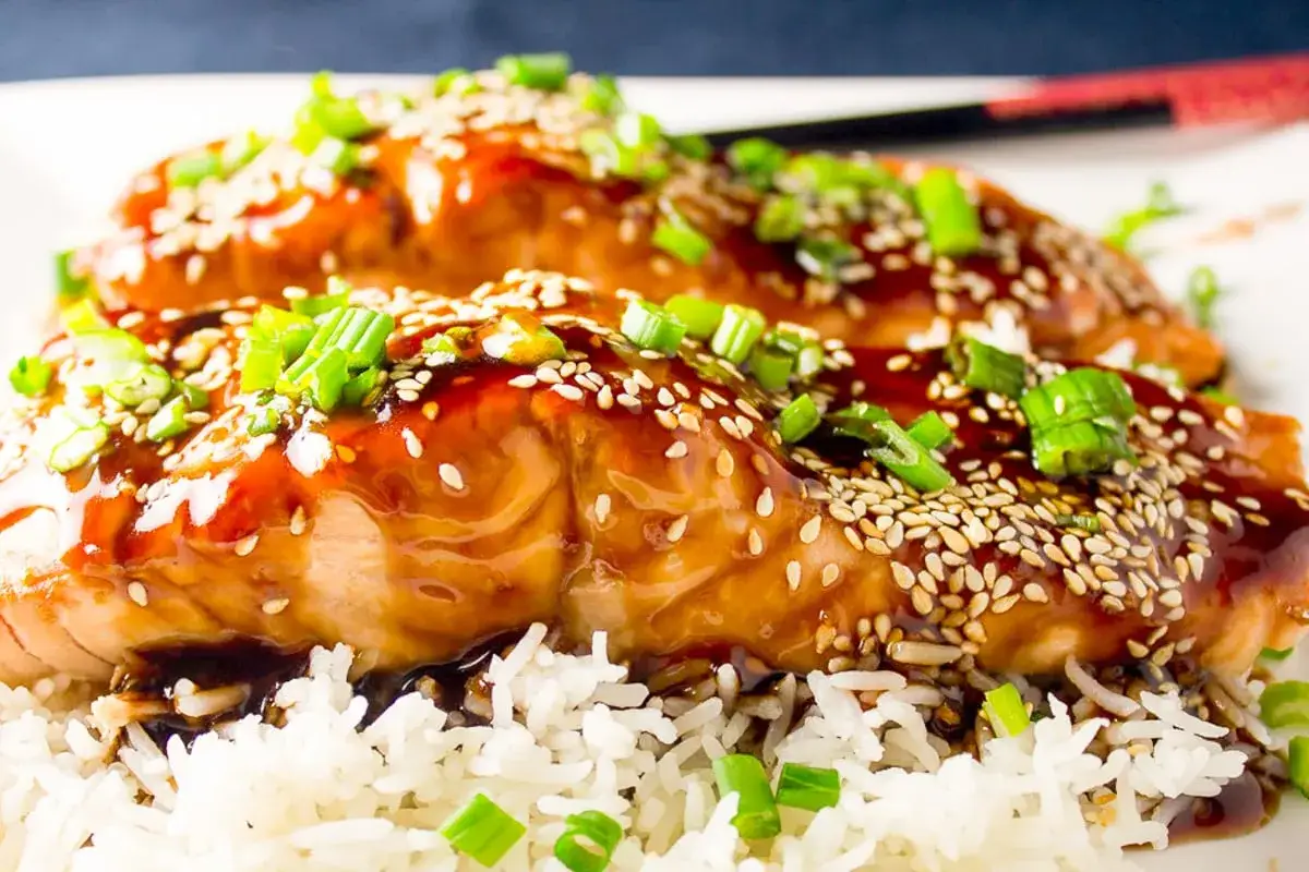 Tv&aring; saftiga fil&eacute;er av teriyaki lax, toppade med sesamfr&ouml;n och gr&ouml;n l&ouml;k, serveras &ouml;ver en b&auml;dd av fluffigt ris.
