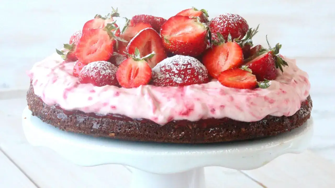 Enkel tårta med chokladbotten, rosa grädde och färska jordgubbar, pudrad med florsocker.
